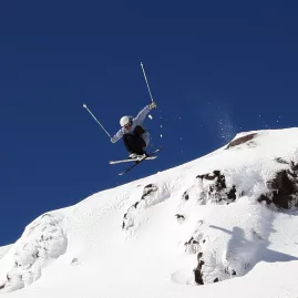 Skier jumping off rocky ledge at Tūroa Ski Field, Mt Ruapehu