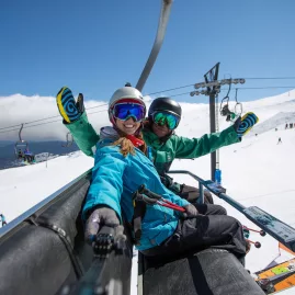 Two skiers smiling on chairlift at Tūroa Ski Area, Mt Ruapehu