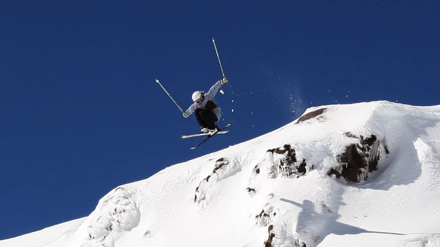 Skier jumping off rocky ledge at Tūroa Ski Field, Mt Ruapehu