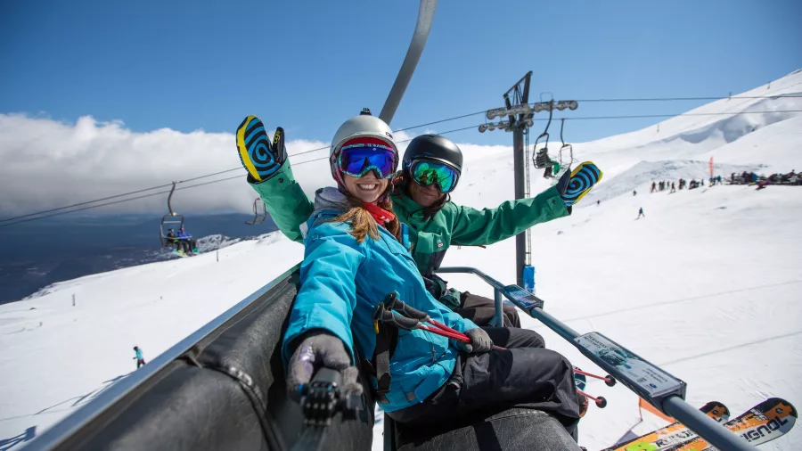 Two skiers smiling on chairlift at Tūroa Ski Area, Mt Ruapehu