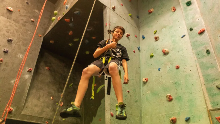 Young climber hanging on the indoor wall at National Park Backpackers Climbing Wall in Waimarino