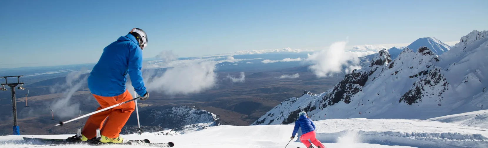 Skiers descending Whakapapa Ski Area with volcanic summit views