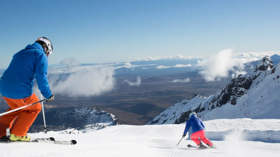 Skiers descending Whakapapa Ski Area with volcanic summit views