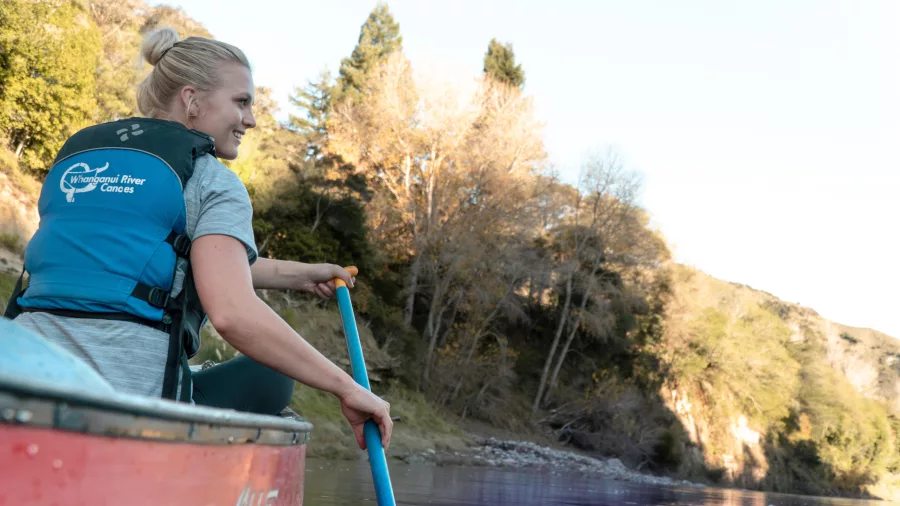 Woman paddling solo in a canoe on the Whanganui River