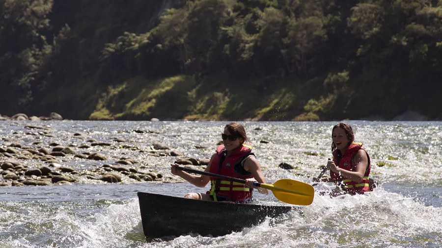 Two women canoeing through choppy water on the Whanganui River