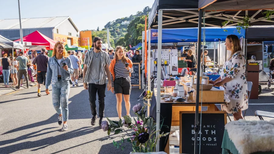 People browsing colourful stalls at the Whanganui River Markets on a sunny morning