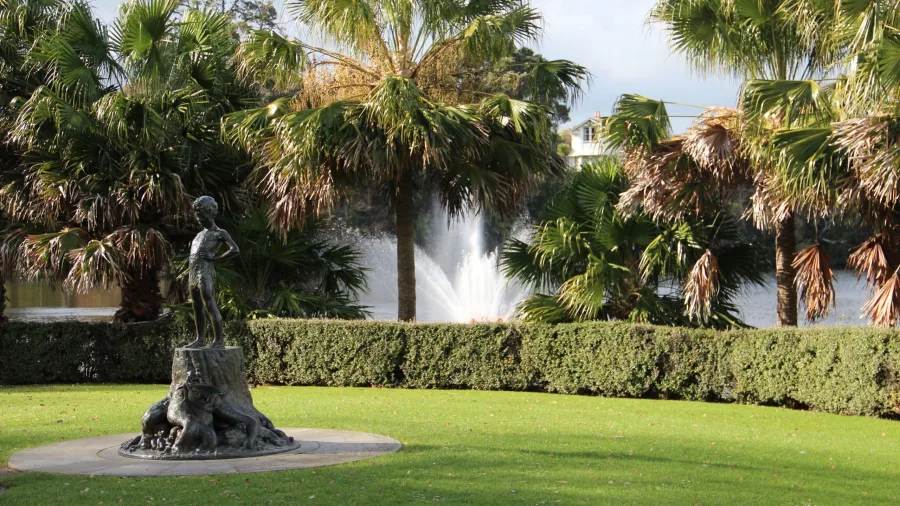 Peter Pan statue surrounded by palm trees and fountain at Virginia Lake in Whanganui