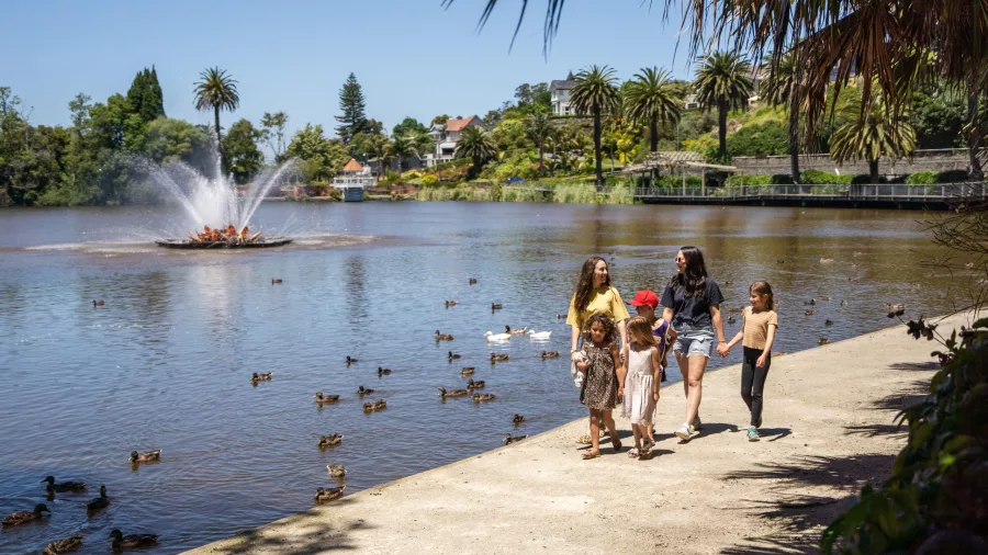 Family walking beside the lake and fountain at Virginia Lake surrounded by ducks and trees