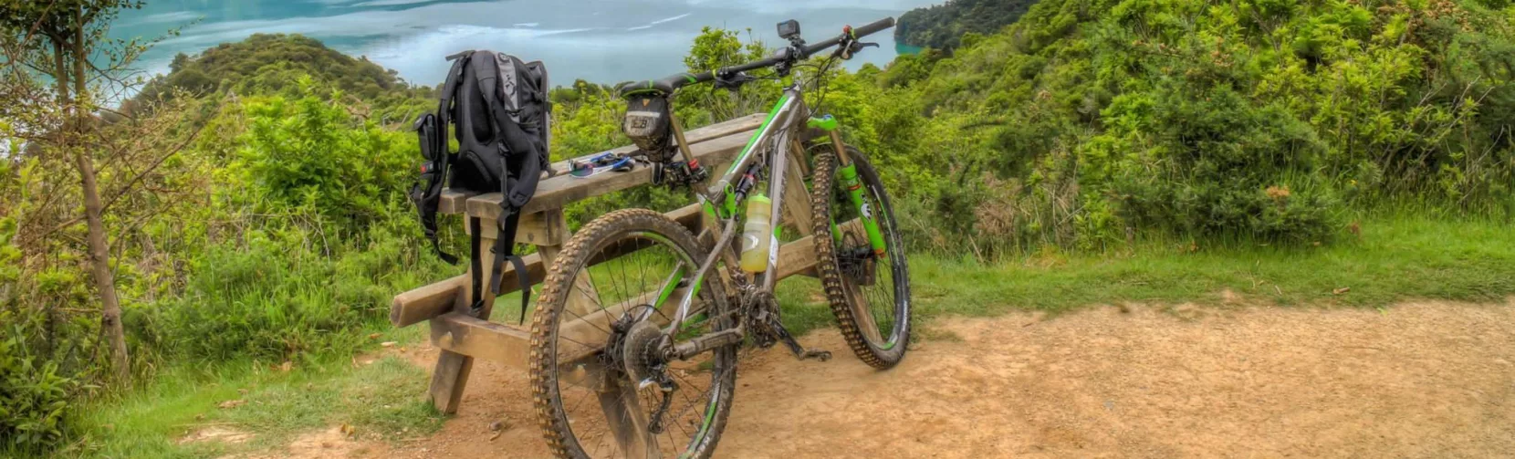 Mountain bike resting against a bench uphill from Anakiwa with views over Kenepuru Sound
