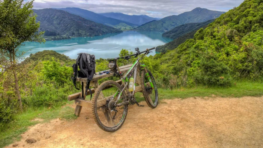 Mountain bike resting against a bench uphill from Anakiwa with views over Kenepuru Sound