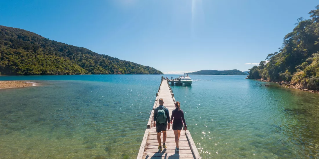 Couple walking along the jetty at Ship Cove on the Queen Charlotte Track
