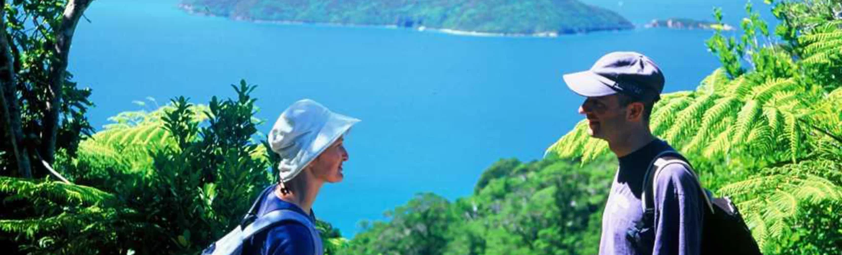 Couple enjoying views from Ship Cove Lookout along the Queen Charlotte Track, Marlborough Sounds