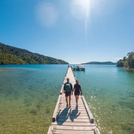 Couple walking along the jetty at Ship Cove on the Queen Charlotte Track