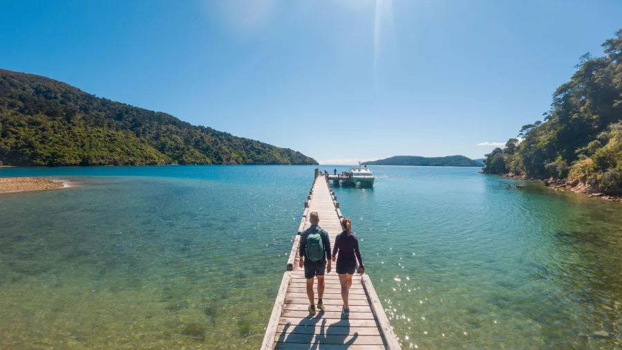 Couple walking along the jetty at Ship Cove on the Queen Charlotte Track