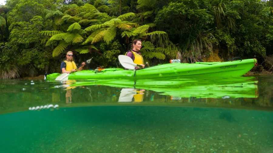 Split-level image showing kayakers above crystal-clear water in Queen Charlotte Sound