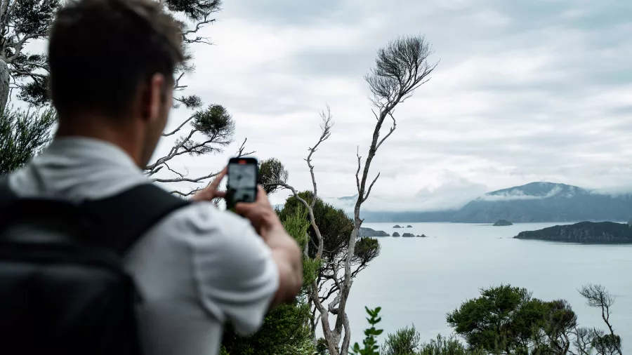 Man photographing the misty view over Marlborough Sounds from Motuara Island.