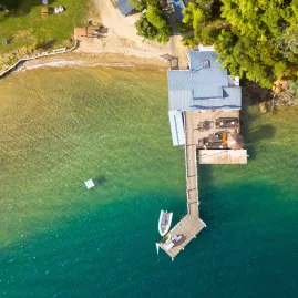 Aerial view of Punga Cove Resort’s jetty and beach surrounded by lush forest.
