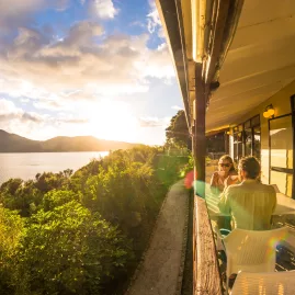 Guests enjoying breakfast on the balcony at Punga Cove Resort with sunrise over Queen Charlotte Sound.