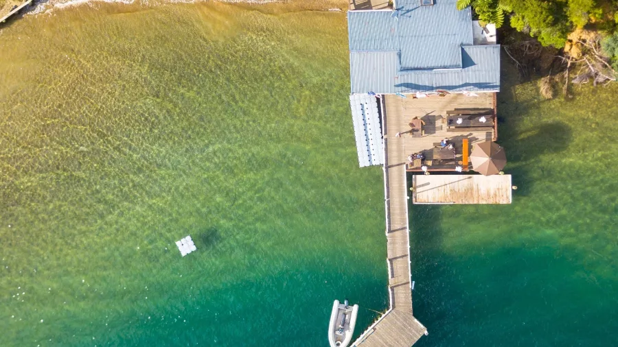 Aerial view of Punga Cove Resort’s jetty and beach surrounded by lush forest.