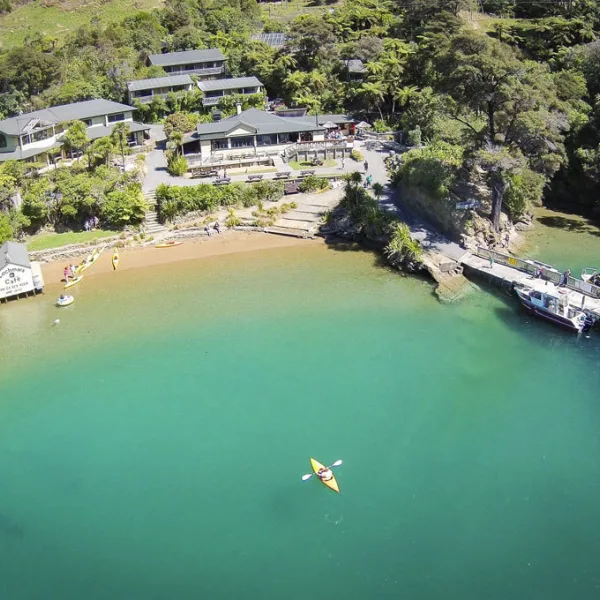 Aerial view of Lochmara Lodge with kayaker in turquoise waters of Queen Charlotte Sound, Marlborough.