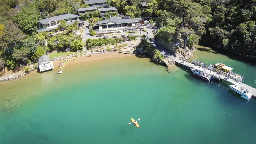 Aerial view of Lochmara Lodge with kayaker in turquoise waters of Queen Charlotte Sound, Marlborough.