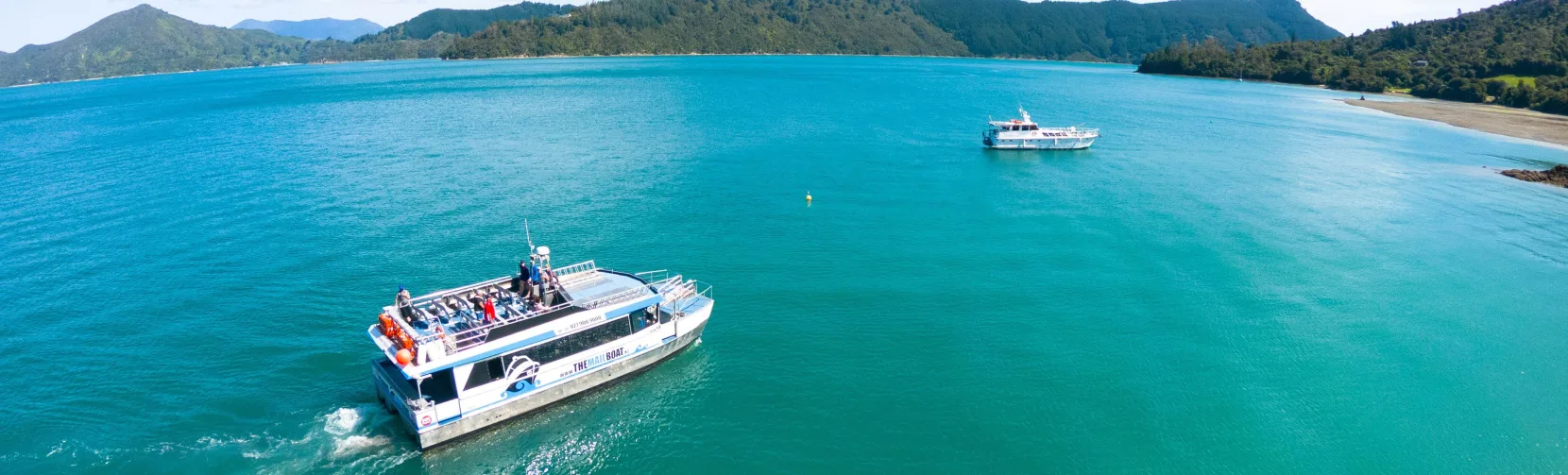Two mailboats cruising through Marlborough Sounds with scenic coastline in the background.