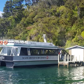 Mailboat arriving at a secluded jetty surrounded by native bush.