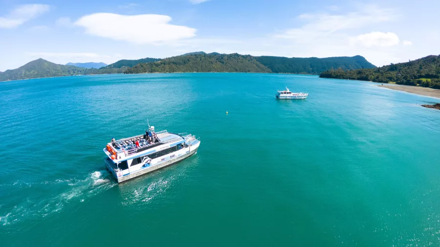 Two mailboats cruising through Marlborough Sounds with scenic coastline in the background.