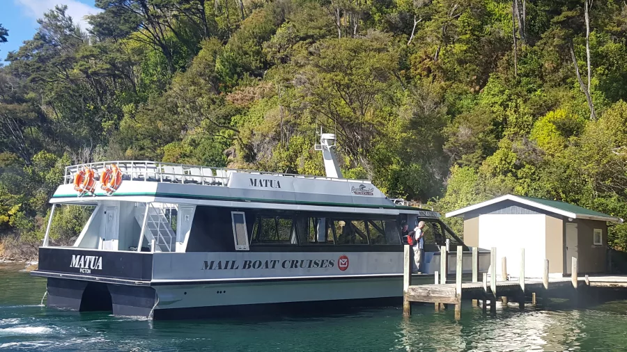 Mailboat arriving at a secluded jetty surrounded by native bush.