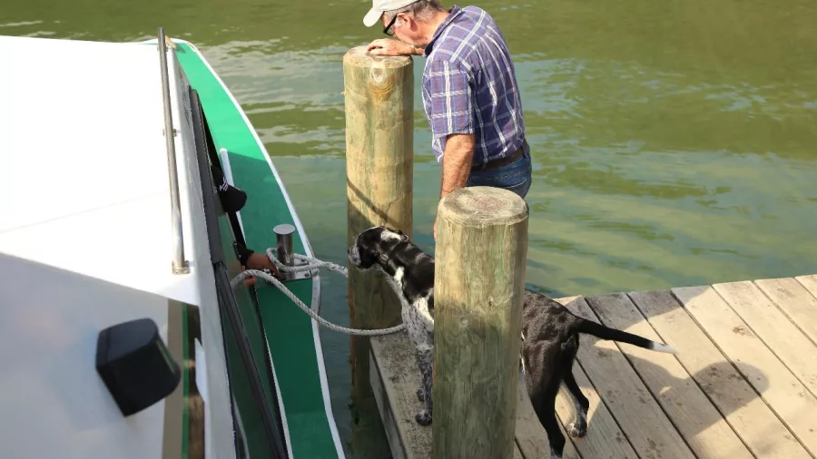 Man and dog waiting beside a Beachcomber Mailboat on a jetty in the Sounds.