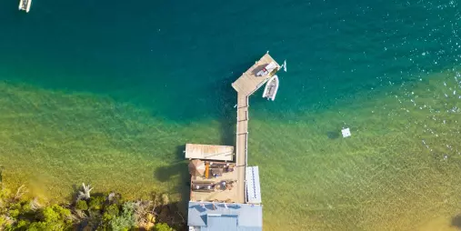 Aerial view of Punga Cove jetty with boats and kayaks on turquoise waters along the Queen Charlotte Track.