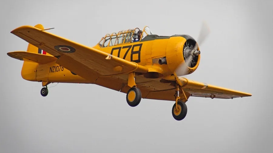 Bright yellow Harvard aircraft flying at the Classic Fighters Omaka Air Show in Blenheim