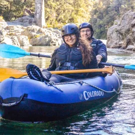 Two people smiling in an inflatable kayak on a Hobbit-themed river tour