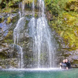 Two people enjoying a waterfall swim stop during the Hobbit Kayak Tour on Pelorus River