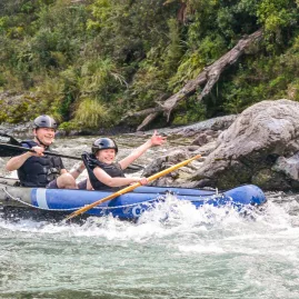 Father and son smiling as they kayak through Pelorus River rapids