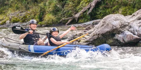 Father and son smiling as they kayak through Pelorus River rapids