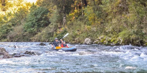 Two people paddling through small rapids on the Pelorus River during a Hobbit-themed kayak tour