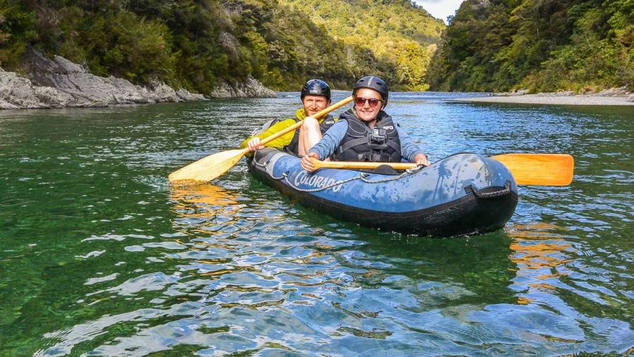 Smiling couple kayaking on the clear waters of the Pelorus River on a guided Hobbit tour