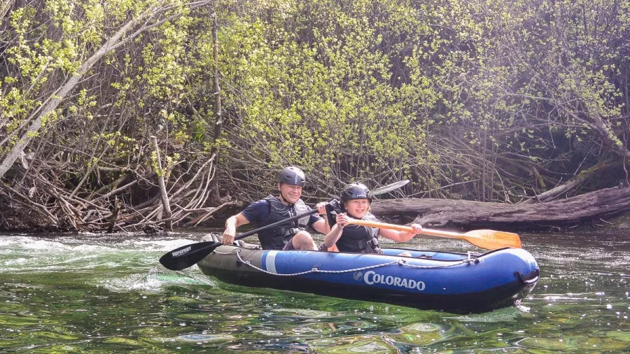 Kayakers paddling along a forested section of the Pelorus River in inflatable rafts