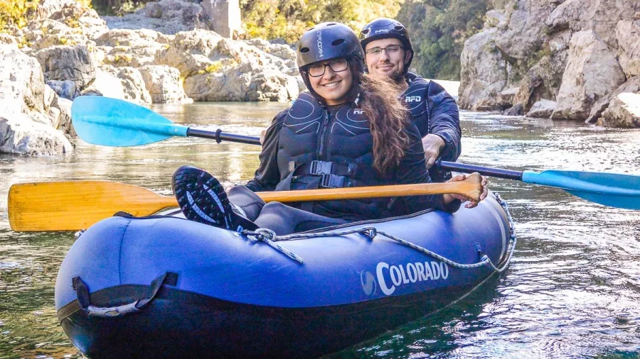 Two people smiling in an inflatable kayak on a Hobbit-themed river tour