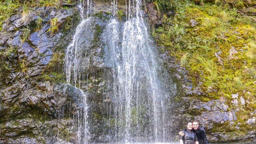 Two people enjoying a waterfall swim stop during the Hobbit Kayak Tour on Pelorus River