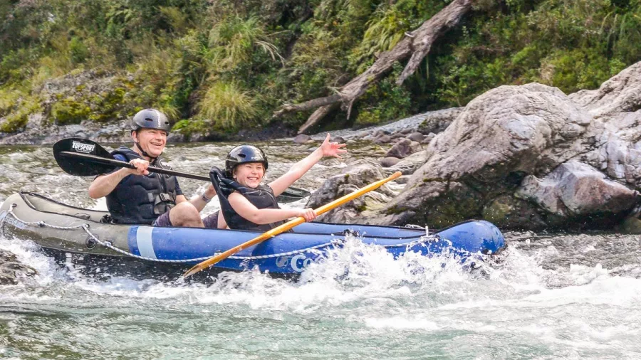 Father and son smiling as they kayak through Pelorus River rapids