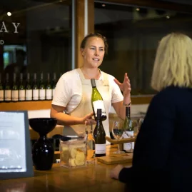 Cellar door host presenting wine at a Marlborough tasting room