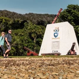 Captain Cook monument at Ship Cove in Marlborough Sounds, with visitors walking by