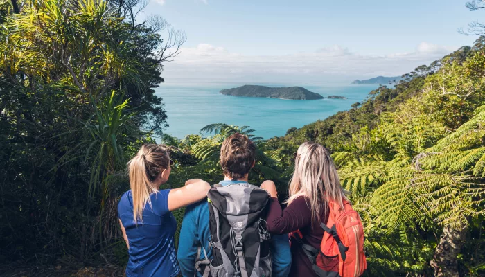 Three hikers with backpacks admire the view over Marlborough Sounds from Queen Charlotte Track