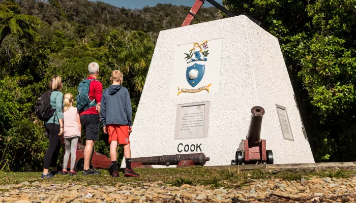Family group admiring the Captain Cook memorial at Ship Cove, surrounded by native forest