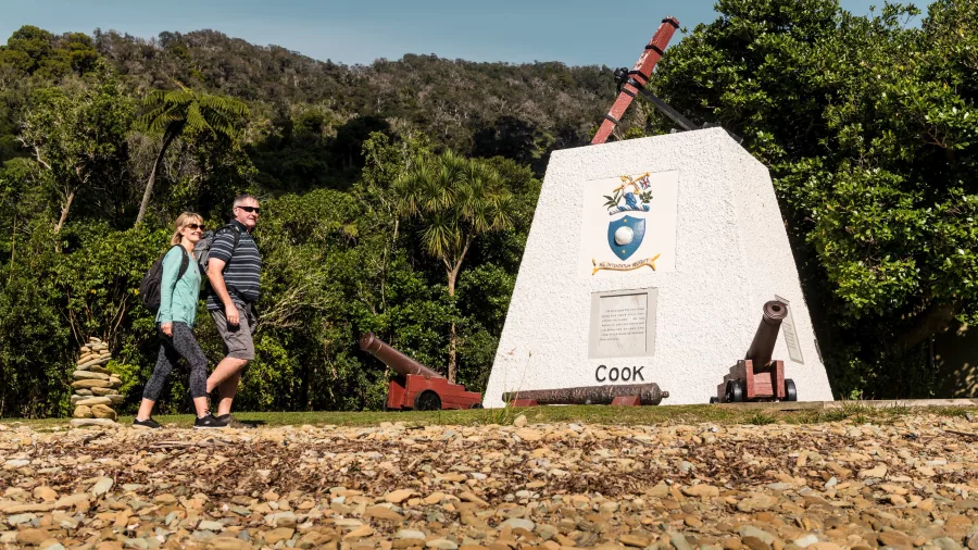 Captain Cook monument at Ship Cove in Marlborough Sounds, with visitors walking by