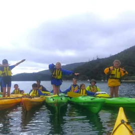 School group standing on kayaks during a fun Marlborough Sounds water activity