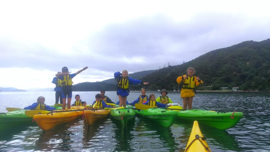 School group standing on kayaks during a fun Marlborough Sounds water activity