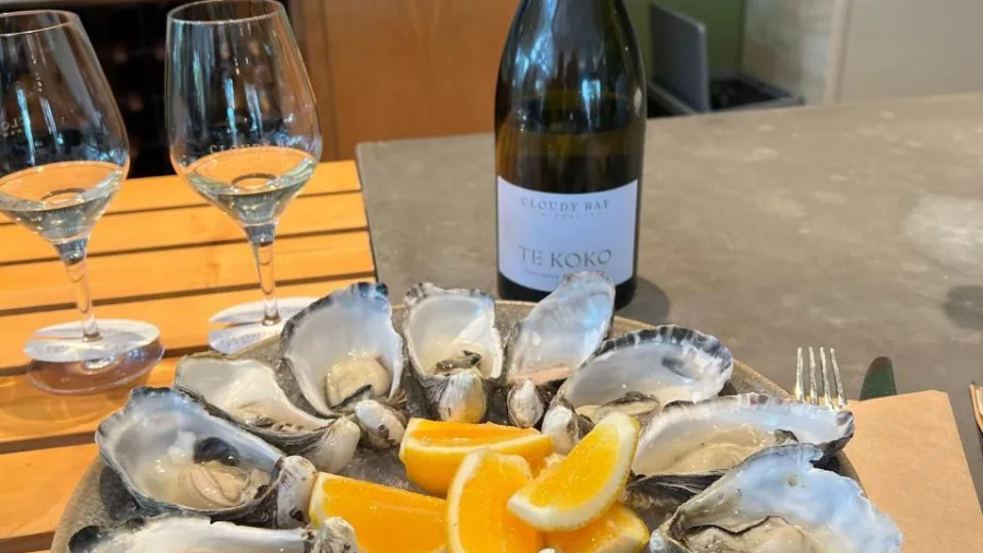 Plate of oysters served with a bottle of Cloudy Bay white wine and two glasses.
